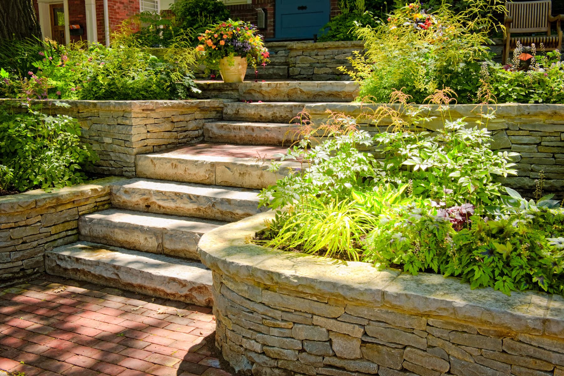 Natural stone retaining wall with stone steps and lush garden plantings at a Lower Mainland home