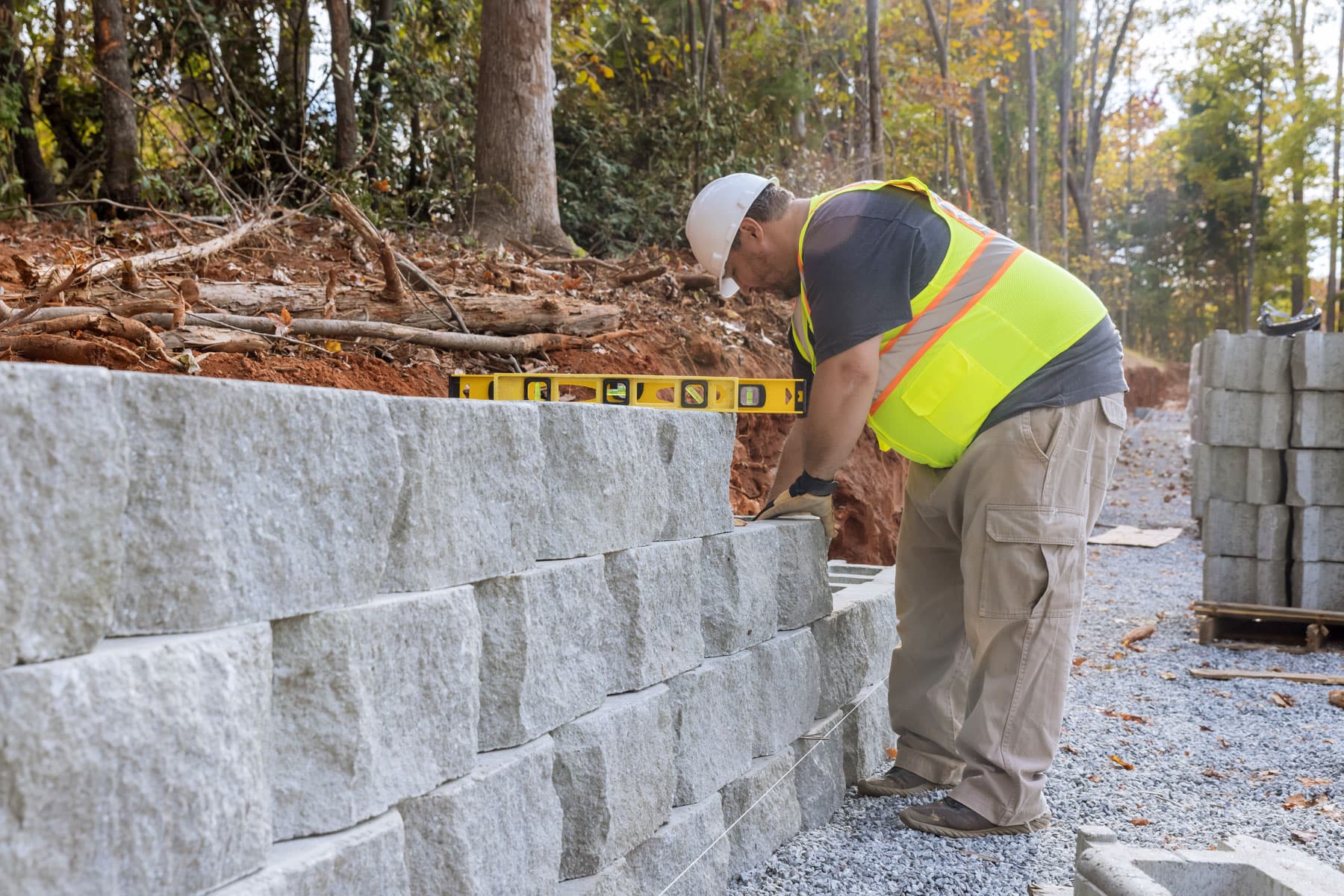 Surrey Retaining Wall Pros installer levelling a granite segmental block retaining wall